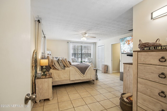 bedroom with light tile patterned flooring, ceiling fan, and a textured ceiling
