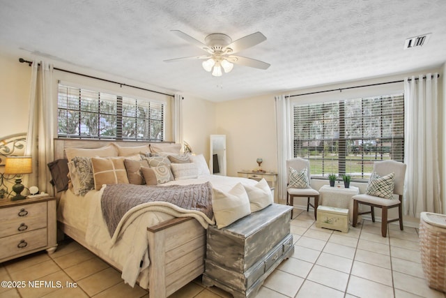 bedroom featuring ceiling fan, a textured ceiling, and light tile patterned floors
