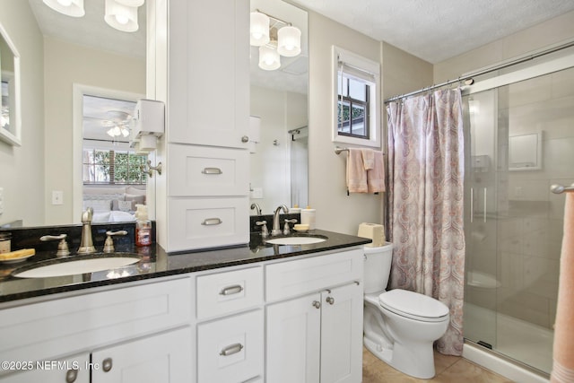 bathroom with tile patterned flooring, vanity, walk in shower, toilet, and a textured ceiling