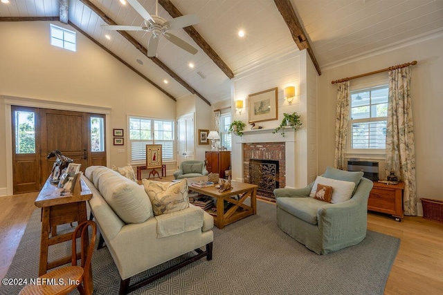 living room with light hardwood / wood-style flooring, high vaulted ceiling, beamed ceiling, and plenty of natural light