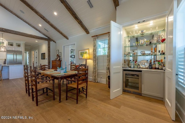 dining area featuring indoor bar, beverage cooler, lofted ceiling with beams, and light hardwood / wood-style flooring