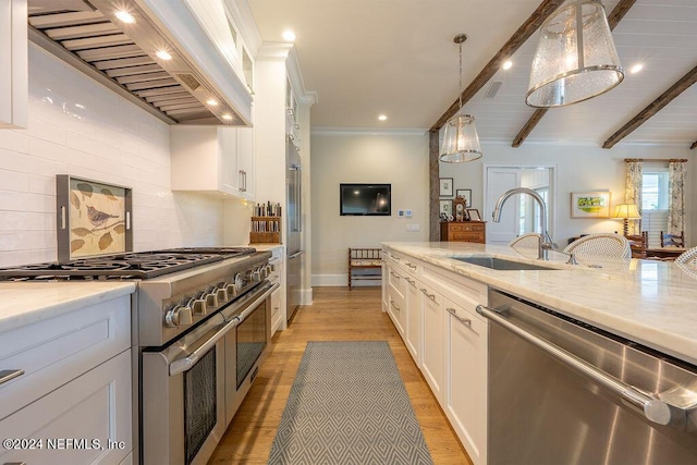 kitchen featuring decorative light fixtures, sink, light stone counters, stainless steel appliances, and custom range hood