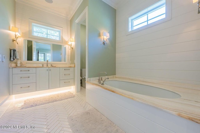 bathroom featuring vanity, toilet, a bath, and a wealth of natural light