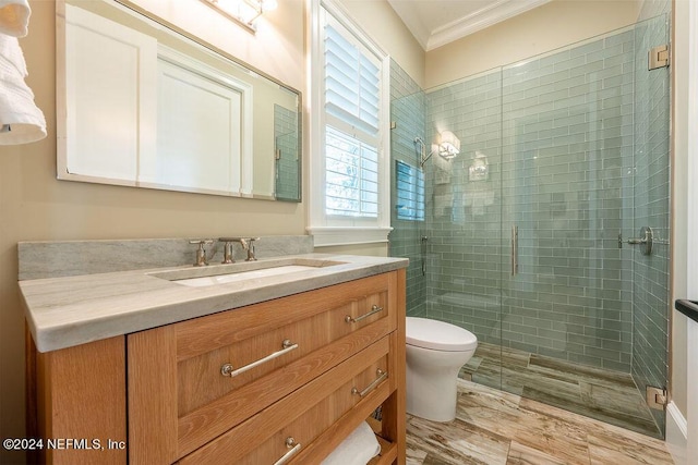 bathroom featuring ornamental molding, toilet, vanity, and a shower with shower door