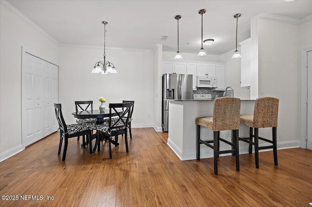 kitchen featuring a kitchen bar, white cabinetry, wood-type flooring, stainless steel fridge with ice dispenser, and kitchen peninsula