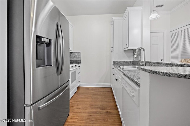 kitchen with sink, white cabinetry, light stone counters, wood-type flooring, and white appliances