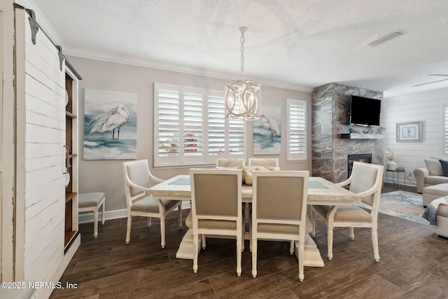 dining room with a barn door, a wealth of natural light, a fireplace, and dark hardwood / wood-style flooring