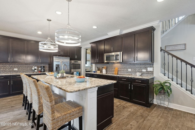 kitchen featuring stainless steel appliances, dark brown cabinets, a center island, and pendant lighting