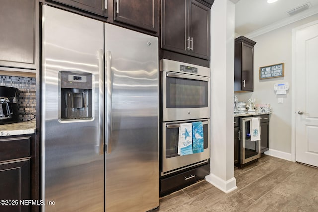 kitchen with appliances with stainless steel finishes, backsplash, beverage cooler, ornamental molding, and dark brown cabinets