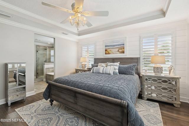 bedroom with ornamental molding, dark hardwood / wood-style floors, connected bathroom, and a tray ceiling