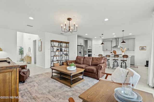 living area with light wood finished floors, baseboards, visible vents, a notable chandelier, and recessed lighting