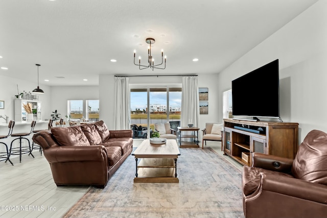 living area featuring recessed lighting, light wood-style flooring, and a notable chandelier