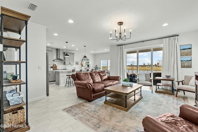 living area with light wood-type flooring, visible vents, a notable chandelier, and recessed lighting