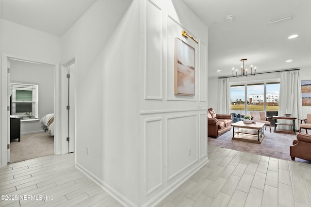 hall with baseboards, recessed lighting, wood tiled floor, and a notable chandelier