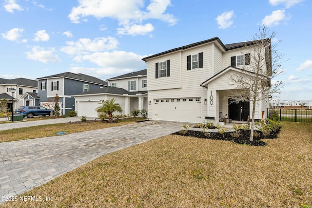 traditional home featuring a residential view, fence, decorative driveway, and a front yard