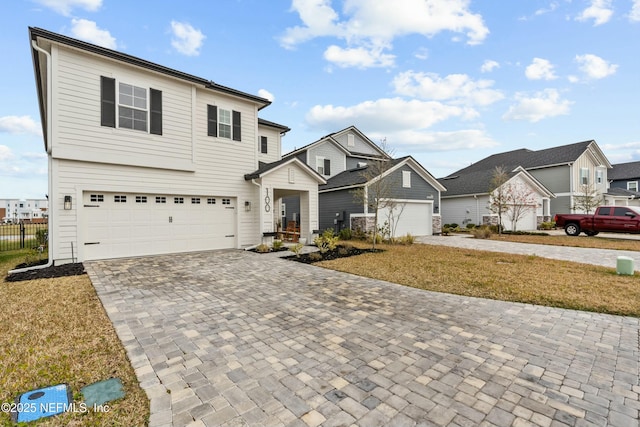 view of front of property with a residential view, decorative driveway, and a front lawn