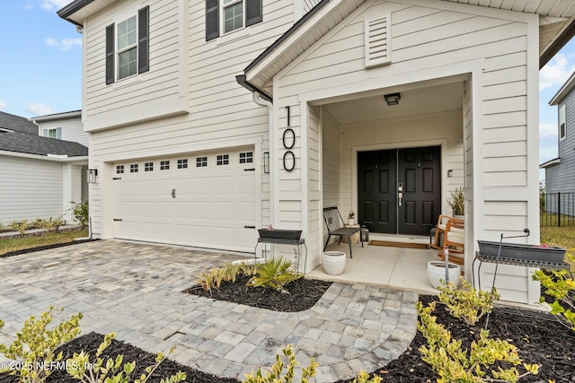 entrance to property featuring a garage and decorative driveway