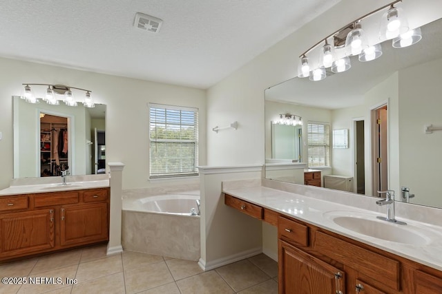 bathroom featuring tile patterned flooring, vanity, a tub, and a textured ceiling