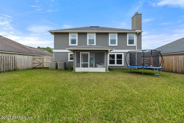 back of house with a trampoline, a lawn, and a sunroom
