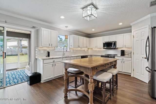 kitchen featuring white cabinetry, appliances with stainless steel finishes, and decorative light fixtures