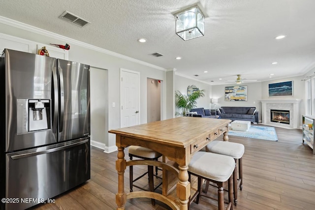dining room with ornamental molding, hardwood / wood-style floors, ceiling fan, and a textured ceiling