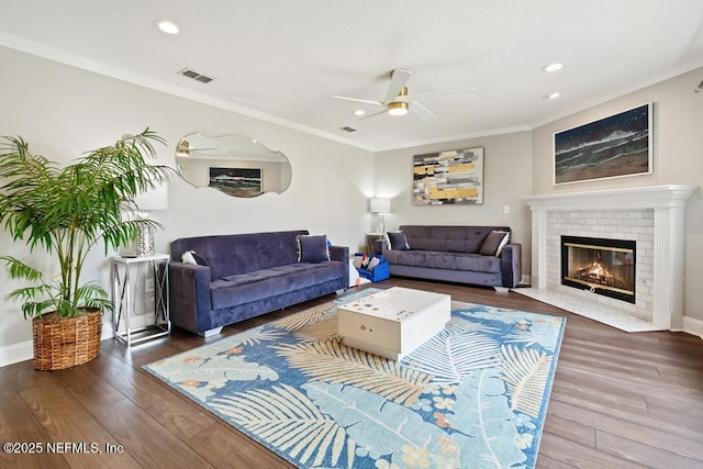 living room featuring crown molding, ceiling fan, a fireplace, and hardwood / wood-style flooring