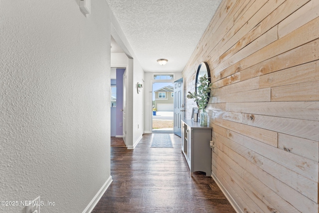 corridor featuring dark hardwood / wood-style floors, wooden walls, and a textured ceiling