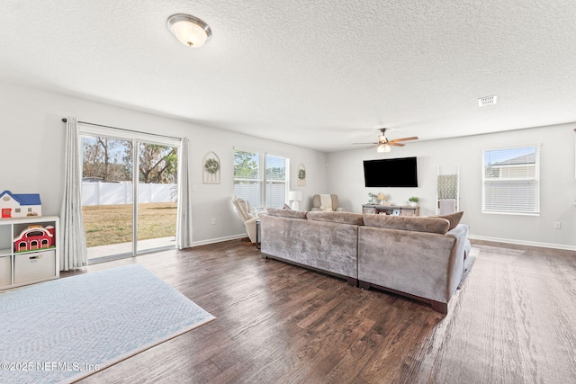 living room with ceiling fan, dark wood-type flooring, and a textured ceiling