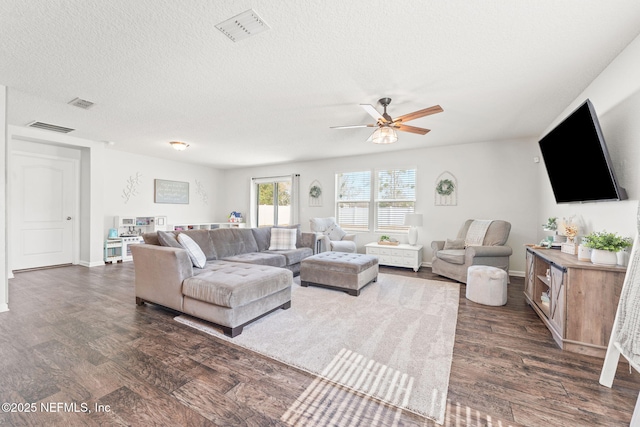 living room featuring dark wood-type flooring, ceiling fan, and a textured ceiling