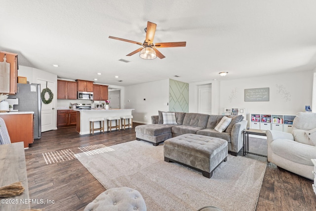 living room featuring dark wood-type flooring, ceiling fan, and a textured ceiling