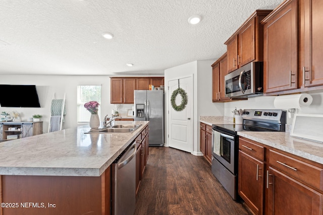 kitchen with stainless steel appliances, dark hardwood / wood-style flooring, sink, and a center island with sink