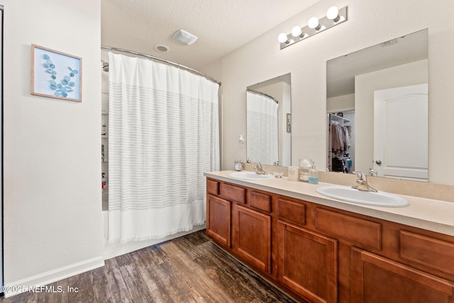 bathroom featuring vanity, hardwood / wood-style floors, a textured ceiling, and shower / tub combo with curtain