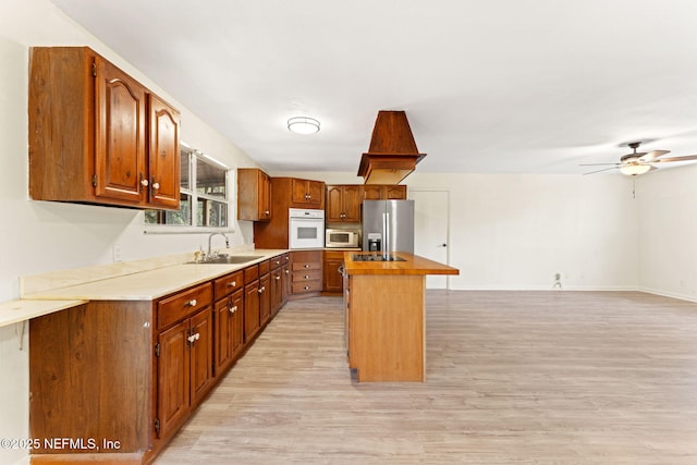 kitchen featuring a center island, stainless steel fridge with ice dispenser, light wood-type flooring, white oven, and a sink