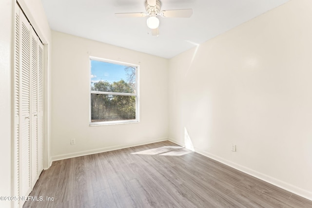 unfurnished bedroom featuring a closet, a ceiling fan, baseboards, and wood finished floors