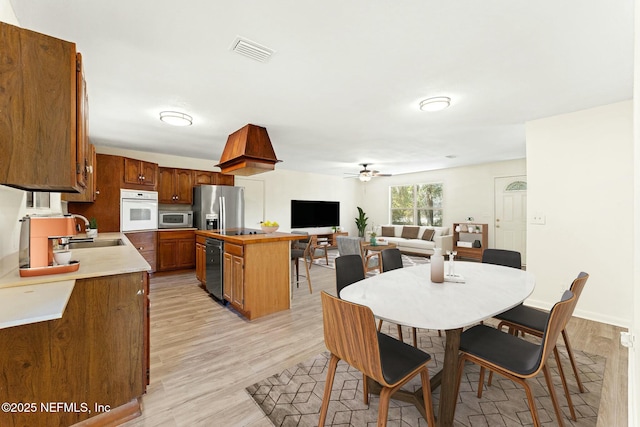 dining space with light wood-type flooring, baseboards, visible vents, and a ceiling fan