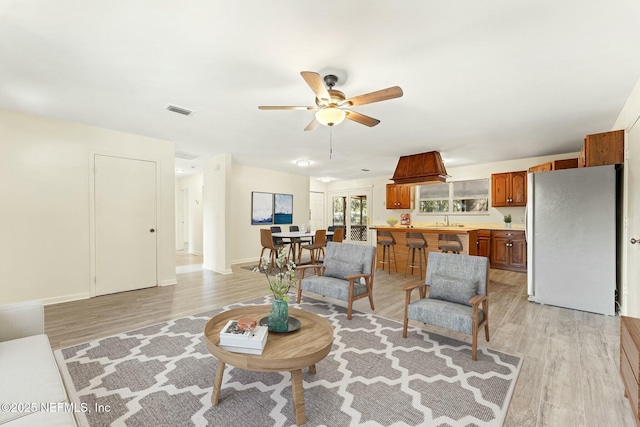 living room with visible vents, baseboards, light wood-type flooring, and ceiling fan