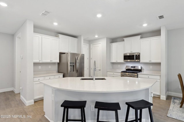 kitchen with white cabinetry, a kitchen island with sink, appliances with stainless steel finishes, and light countertops