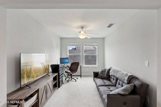 office with visible vents, a ceiling fan, light carpet, a textured ceiling, and baseboards