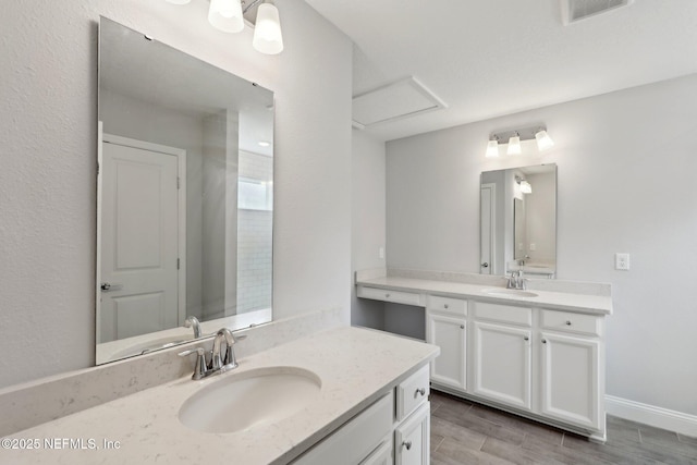 full bath with baseboards, visible vents, two vanities, and a sink