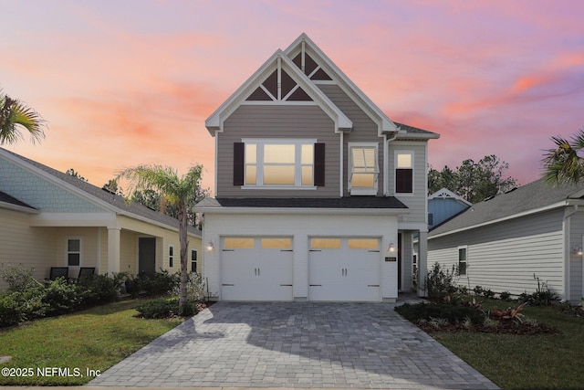 view of front of property featuring a yard, decorative driveway, and an attached garage