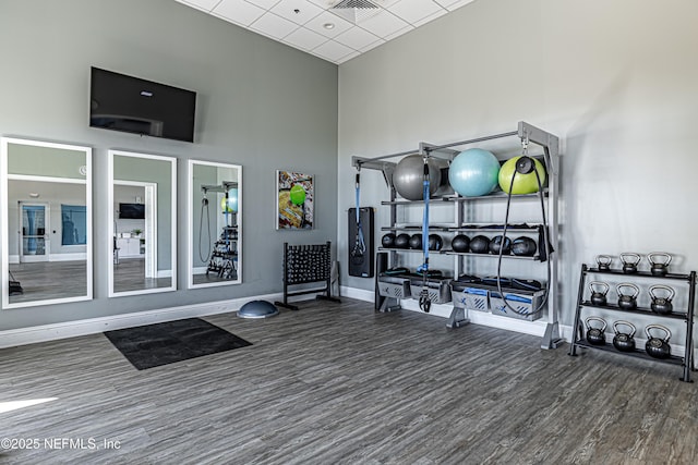 exercise room featuring a high ceiling, wood finished floors, visible vents, and baseboards