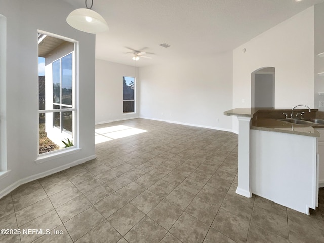 unfurnished living room with dark tile patterned floors, sink, and ceiling fan