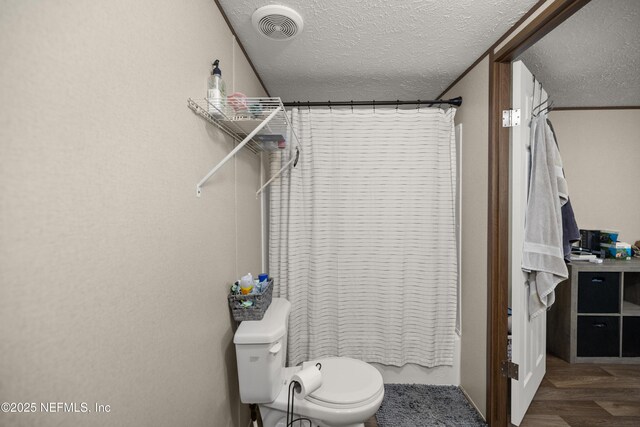 bathroom featuring shower / tub combo, hardwood / wood-style floors, toilet, and a textured ceiling