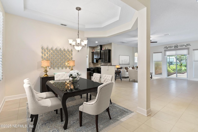 dining room with light tile patterned floors, a raised ceiling, visible vents, an inviting chandelier, and baseboards