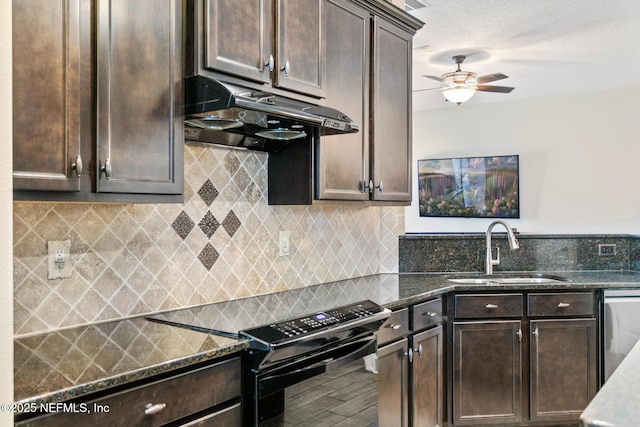 kitchen featuring dark brown cabinetry, under cabinet range hood, a sink, black electric range, and dark stone countertops
