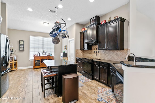 kitchen featuring tasteful backsplash, visible vents, a kitchen island, black range with electric cooktop, and a kitchen bar