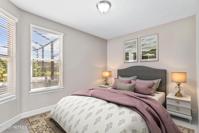 carpeted bedroom featuring a textured ceiling and baseboards