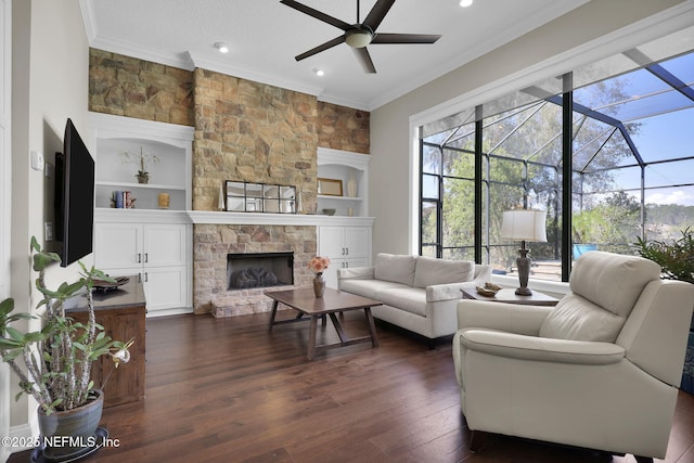 living room with ornamental molding, built in features, dark hardwood / wood-style flooring, and a fireplace