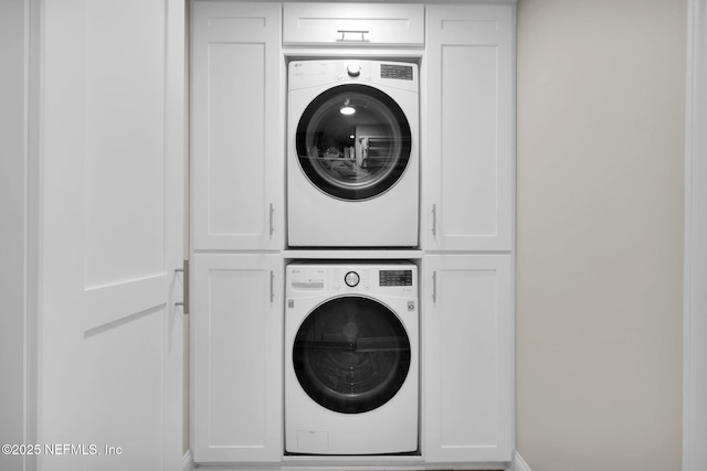 laundry area with stacked washer and dryer and cabinets