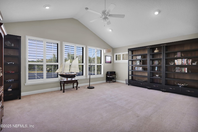 sitting room with ceiling fan, light colored carpet, and high vaulted ceiling